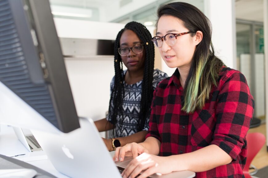 Two people looking at multiple computer screens.